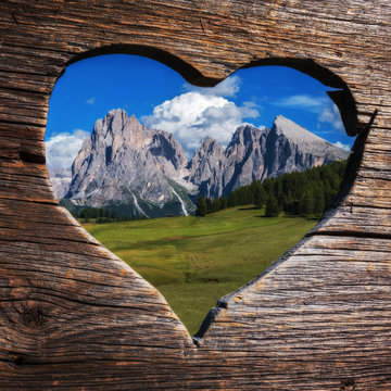 Mit lieben Grüßen aus den Dolomiten in Italien. Ein herzförmiger Blick durch die Bank auf die Berge.  - © gljivec - stock.adobe.com