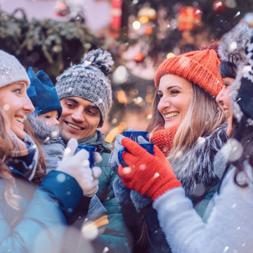 eine Gruppe von Freunden trinkt in der Kälte Glühwein auf einem Weihnachtsmarkt