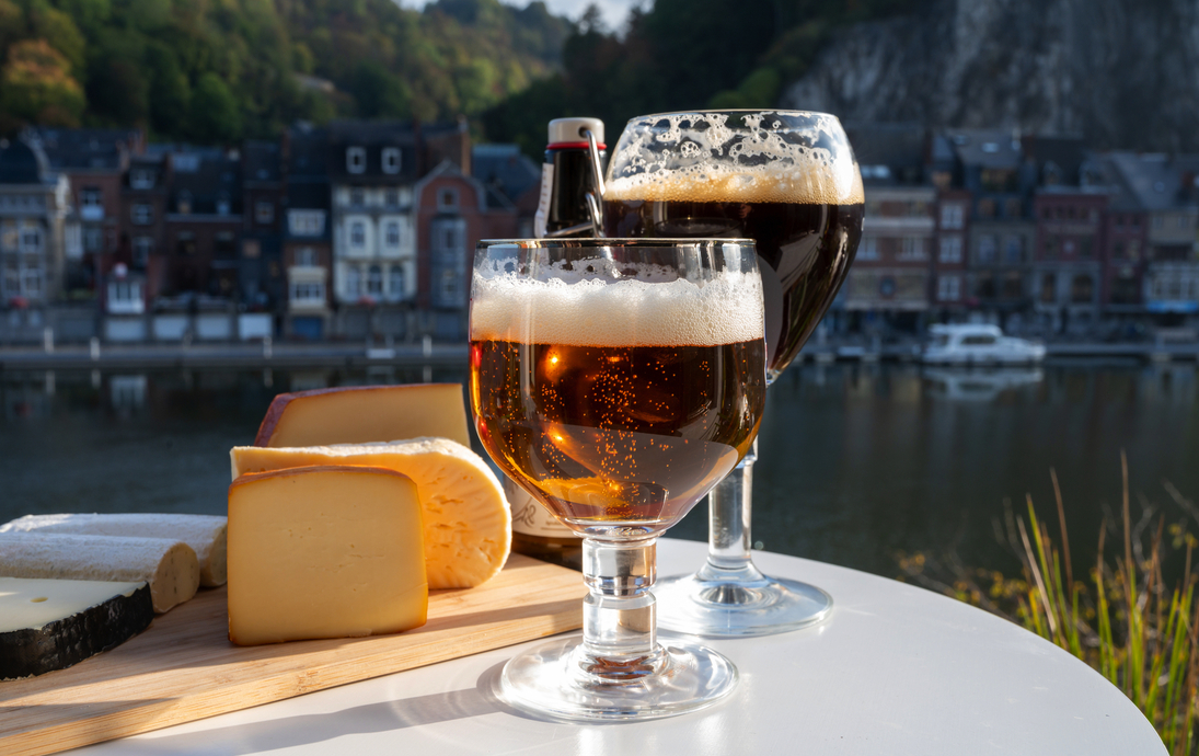 Glas belgisches Abteibier und Verkostung von Käse aus Trappistenbier und feinen Kräutern mit Blick auf die Maas in Dinant